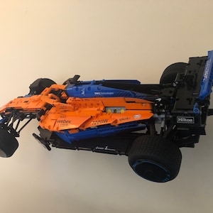 May include: A blue and orange Lego Formula 1 race car with various sponsors' logos, including Dell Technologies, Webex, Splunk, and Hilton.