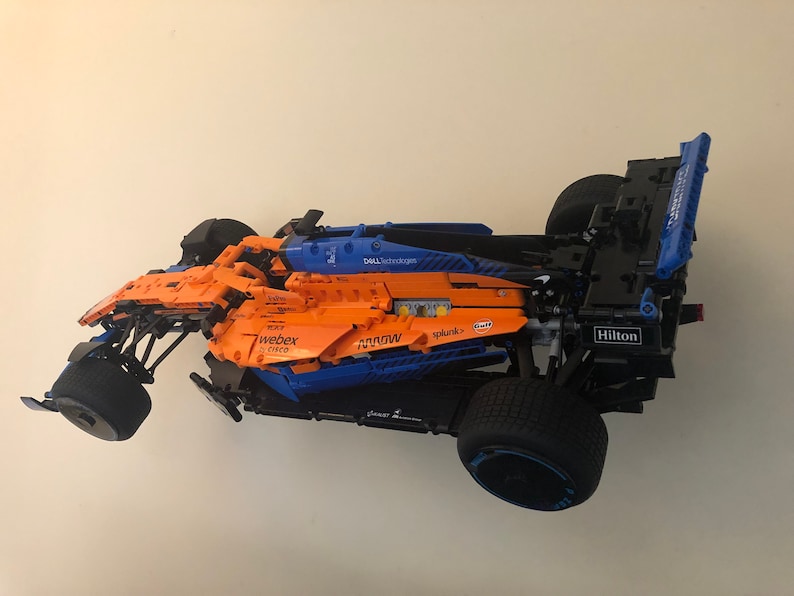 May include: A blue and orange Lego Formula 1 race car with various sponsors' logos, including Dell Technologies, Webex, Splunk, and Hilton.