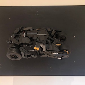 May include: A black Lego model of the Batmobile from the Batman movie franchise. The model is displayed on a black background.