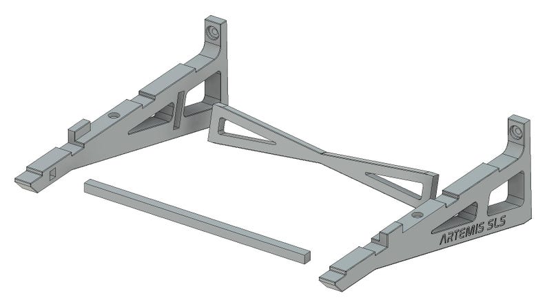 May include: A gray 3D printed stand with two angled supports and a connecting bar. The stand is labeled "ARTEMIS SLS".