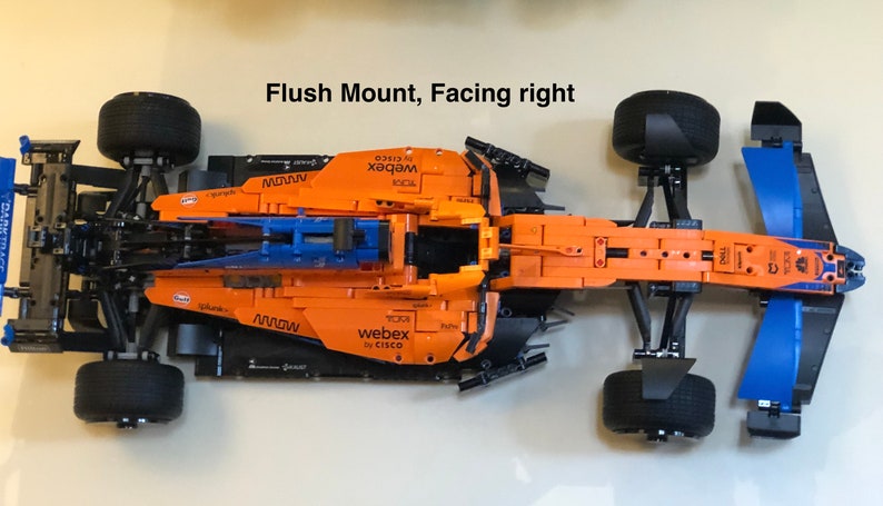 May include: A black and orange Lego McLaren Formula 1 race car with blue wings. The car has the words "webex by CISCO" and "MOWW" printed on the side. The car is in a flush mount position, facing right.
