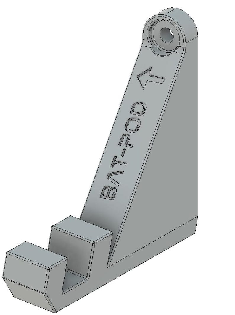 Op de afbeelding: Een grijze plastic wandbeugel met de tekst "BAT-POD" en een pijl die omhoog wijst. De beugel heeft een haak aan de onderkant om een object aan op te hangen.