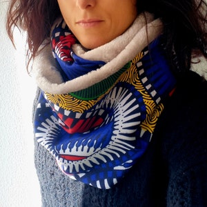 Pode incluir: Uma echarpe infinita com padrão azul, branco, amarelo, vermelho e verde com forro de lã branca.