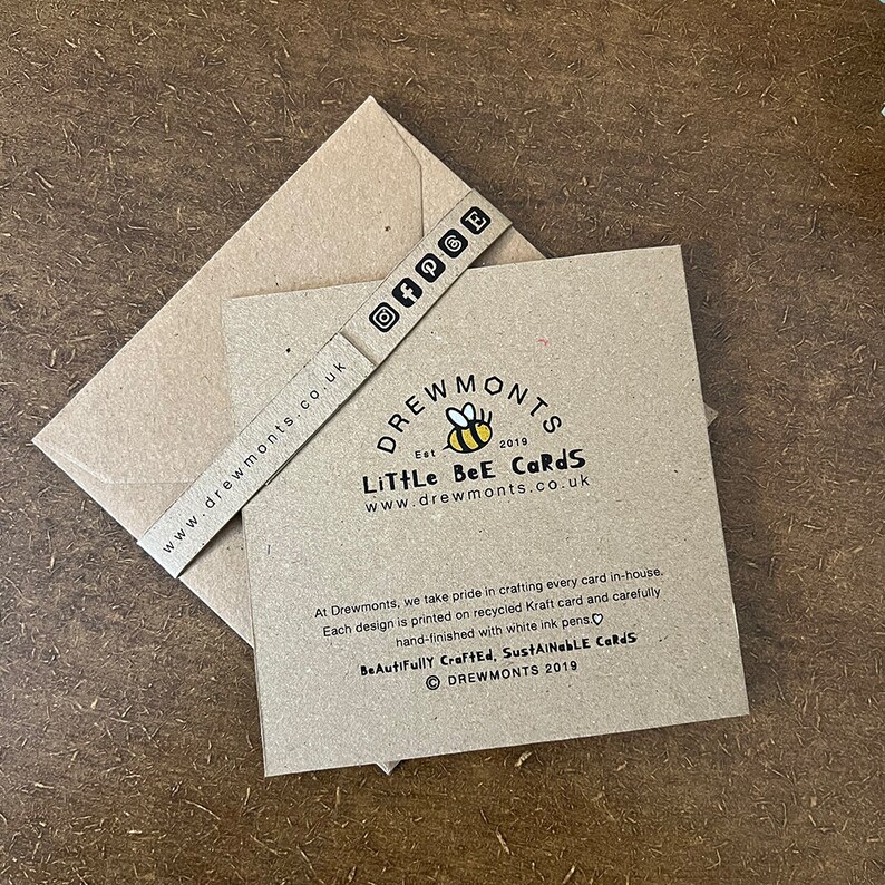 May include: A brown card with a bee logo and the text "Drewmonts Est 2019 Little Bee Cards www.drewmonts.co.uk". The card also includes the text "At Drewmonts, we take pride in crafting every card in-house. Each design is printed on recycled Kraft card and carefully hand-finished with white ink pens. Beautifully Crafted, Sustainable Cards &copy; Drewmonts 2019".