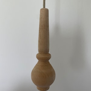 May include: A wooden light pull with a bulbous bottom and a cylindrical top. The pull is attached to a string.