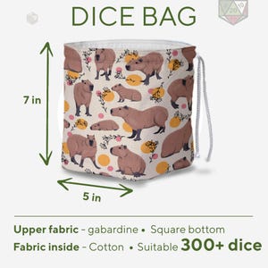 May include: A beige dice bag with a capybara pattern, measuring 7 inches high and 5 inches wide. The bag features a drawstring closure and is made of gabardine fabric on the outside and cotton on the inside. The text "DICE BAG" is at the top.