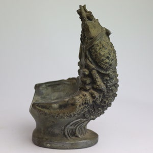 May include: A bronze sculpture of a fish with an open mouth, forming a small bowl. The fish is detailed with scales and fins, and the bowl is perfect for holding small items.
