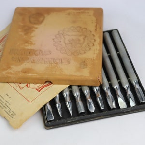 May include: A set of 10 metal carving tools in a black case with a brown cardboard box labelled "НАБОР ШИКАНОВ".