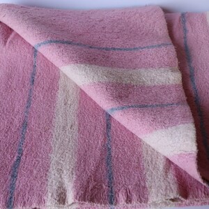 Puede incluir: Una manta de rayas rosa y blancas con rayas azules. La manta est&aacute; doblada por la mitad y tiene una textura suave y peluda.