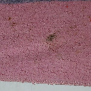 Puede incluir: Primer plano de una tela rosa con una superficie texturizada. La tela tiene algunas manchas oscuras y una mancha marr&oacute;n claro.