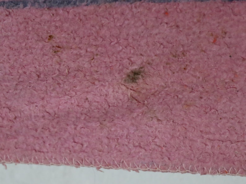 Puede incluir: Primer plano de una tela rosa con una superficie texturizada. La tela tiene algunas manchas oscuras y una mancha marr&oacute;n claro.