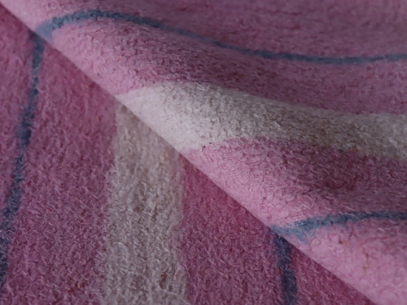 Puede incluir: Primer plano de una tela de rayas rosa y blancas con una raya azul. La tela tiene una textura peluda.