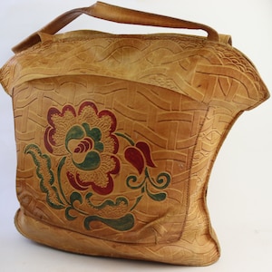 May include: A tan leather tote bag with a floral design. The bag has a woven pattern and a single strap.
