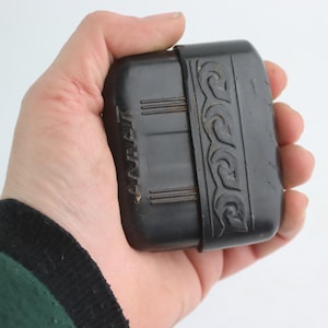 Könnte beinhalten: Ein schwarzes Plastiketui mit einem dekorativen Design und dem Wort "AVENT" auf der Seite.