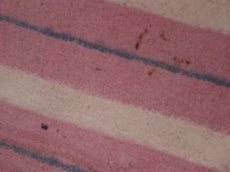 Puede incluir: Primer plano de una tela de rayas rosas y blancas con una superficie texturizada. La tela tiene una sutil raya azul que corre diagonalmente a trav&eacute;s de la superficie.
