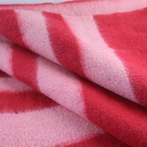 May include: A red and pink striped blanket with a soft, fuzzy texture.