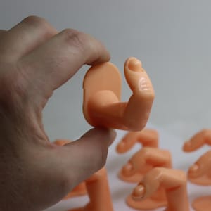 May include: A set of eight flesh-toned finger mannequins for displaying nail art and jewellery. The mannequins are made of a soft, flexible material and are designed to look like real fingers.