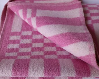 Peut inclure: Une couverture à carreaux rose et blanc pliée en trois. La couverture est faite d'un matériau doux et duveteux.