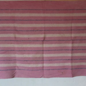 Puede incluir: Una manta de rayas rosa y blancas con textura tejida. La manta tiene un aspecto descolorido y est&aacute; hecha de lana.