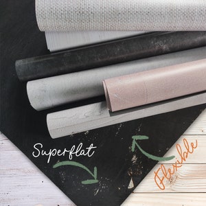 May include: A close-up of a stack of different coloured, textured, and flexible backdrops. The backdrops are rolled up and the text "Superflat" and "Flexible" is written on a black surface.