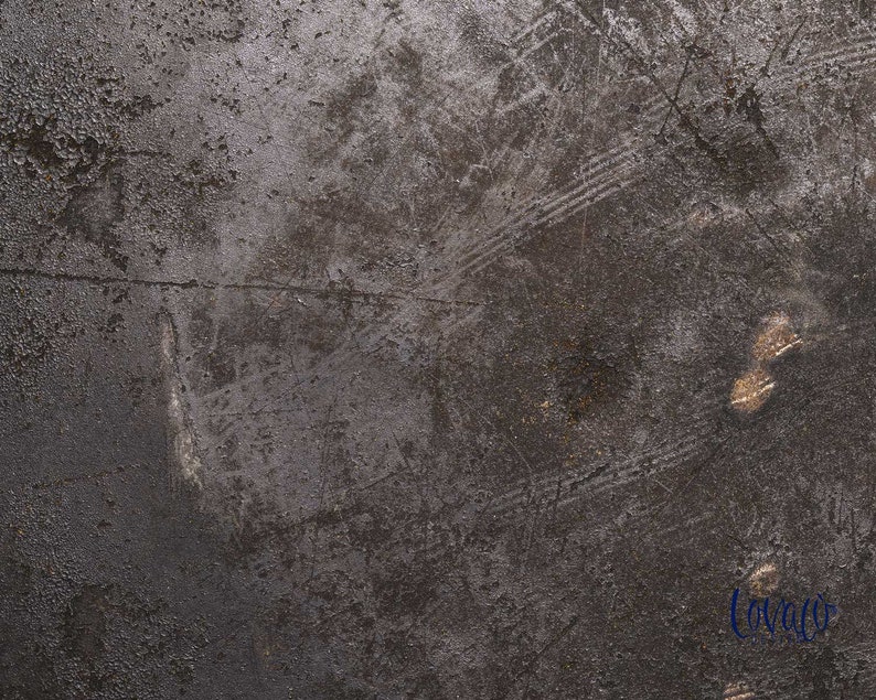 May include: A close-up of a dark gray textured surface with scratches and marks. The surface has a metallic sheen and appears to be made of metal.