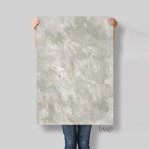 Puede incluir: Una impresión grande y abstracta con un fondo texturizado gris y blanco con sutiles toques de verde y marrón. La impresión tiene un aspecto desgastado y envejecido, que recuerda al hormigón o la piedra erosionada.