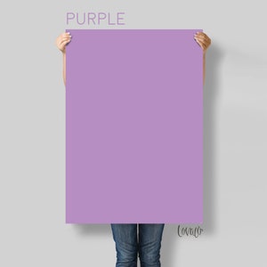 May include: A person holding a large, solid purple poster with the word "PURPLE" printed at the top and the word "Love" written in cursive at the bottom.