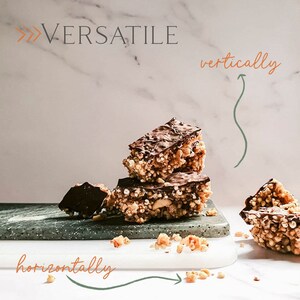 May include: A stack of three chocolate-covered granola bars on a grey and white surface. The bars are made with puffed rice, nuts, and chocolate. The text "VERSATILE" is written in orange at the top of the image. The text "vertically" is written in orange and "horizontally" is written in orange with arrows pointing to the bars.