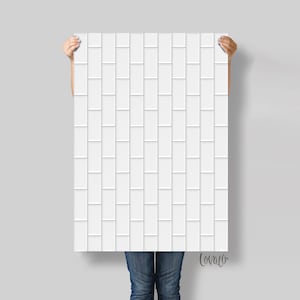 May include: A white rectangular panel with a brick-like pattern is held up. The panel features a repeating design of elongated rectangles, creating a textured, three-dimensional effect. The panel is held against a light grey background.