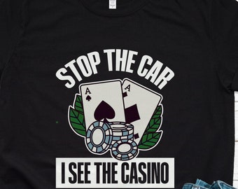 May include: Black t-shirt with white text that says "Stop the car I see the casino". The design includes two playing cards, an ace of spades and an ace of clubs, and a pile of poker chips.
