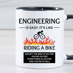 May include: White ceramic mug with a black rim and handle. The mug has a black and white graphic that says "Engineering is easy. It's like riding a bike" with a picture of a person riding a bike on fire. The text below the graphic says "Except the bike is on fire, you're on fire, everything is on fire, and you're in hell."