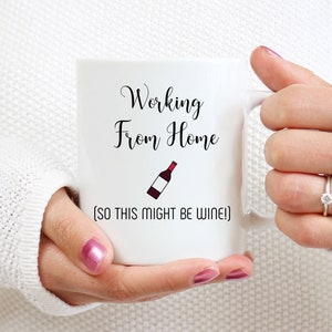 May include: White ceramic mug with the text "Working From Home (So this might be wine)" and a small illustration of a bottle of wine.