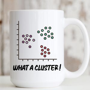 May include: A white ceramic mug featuring a black graphic of a scatter plot with three distinct groups of colored dots in purple, green, and red. Below the graph, the text "WHAT A CLUSTER!" is printed in bold, black, uppercase sans-serif letters.