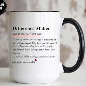 May include: A white ceramic mug with a black handle and rim featuring the printed text Difference Maker, a dictionary-style definition, and the name Samantha followed by a small red heart icon. A circular badge in the corner reads Other Colors Available.