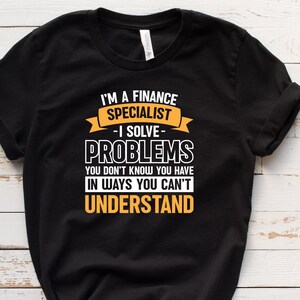 May include: Black t-shirt with a yellow graphic that reads "I'm a finance specialist - I solve problems you don't know you have in ways you can't understand."