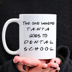 May include: White ceramic mug with a black design that says "The One Where Tanya Goes To Dental School" in a font reminiscent of the popular TV show "Friends".