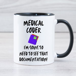 Puede incluir: Taza de café blanca con borde y asa negros. La taza tiene un gráfico en blanco y negro que dice "Medical Coder I'm going to need to see that documentation!" con un icono de carpeta morado.