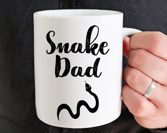May include: White ceramic mug with a black snake design and the text "Snake Dad".