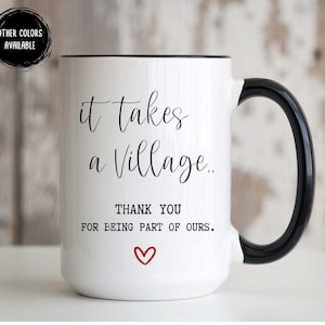 May include: White ceramic coffee mug with a black rim and handle. It features black text that reads "it takes a village.. THANK YOU FOR BEING PART OF OURS." with a red heart.