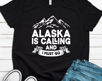 May include: Black t-shirt with a white graphic of mountains and the text "Alaska is calling and I must go".