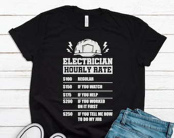 May include: Black t-shirt with the text "ELECTRICIAN HOURLY RATE" and a graphic of a hard hat and lightning bolts. The shirt lists hourly rates for different levels of involvement, from $100 for regular work to $250 if you tell the electrician how to do their job.