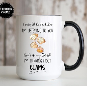 May include: White ceramic mug with a black handle and rim. The mug features the text "I might look like I'm listening to you but in my head I'm thinking about CLAMS" with a graphic of clams.