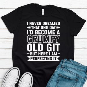 May include: Black t-shirt with white text that reads "I never dreamed that one day I'd become a grumpy old git - but here I am - perfecting it."