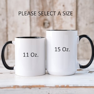 K&ouml;nnte beinhalten: Zwei wei&szlig;e Keramikbecher mit schwarzen Griffen und schwarzen R&auml;ndern. Der Becher links ist 11 oz und der Becher rechts ist 15 oz.