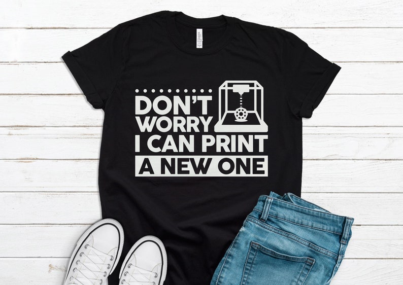 Może przedstawiać: Czarny T-shirt z białym nadrukiem przedstawiającym drukarkę 3D i tekstem "Nie martw się, mogę wydrukować nowy".