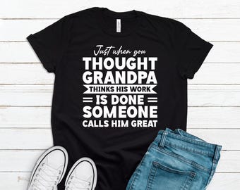 May include: Black t-shirt with white text that reads "Just when you THOUGHT GRANDPA THINKS HIS WORK = IS DONE = SOMEONE CALLS HIM GREAT".