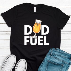 May include: Black t-shirt with white text that reads "Dad Fuel" and a cartoon image of a beer glass.