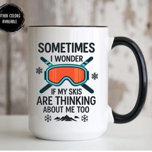 May include: White ceramic mug with a black handle and rim. The mug features the text "SOMETIMES I WONDER IF MY SKIS ARE THINKING ABOUT ME TOO" along with a graphic of ski goggles and snowflakes. A black circle with the text "OTHER COLORS AVAILABLE" is in the upper left.