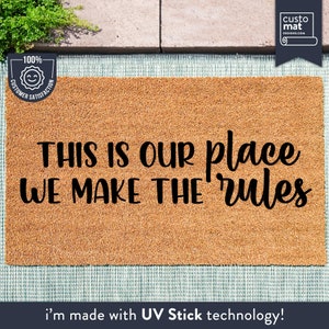 May include: A brown coir doormat with the text "THIS IS OUR place WE MAKE THE rules" in black lettering. The mat has a 100% customer satisfaction guarantee.