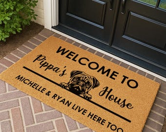 Könnte beinhalten: Rechteckige Fußmatte mit dem Text "WELCOME TO Pippa's House" und "MICHELLE & RYAN LIVE HERE TOO" in Schwarz. Eine Mops-Illustration ist mittig auf der Matte platziert. Die Matte hat eine natürliche, beige Farbe und liegt auf einem Ziegelboden.